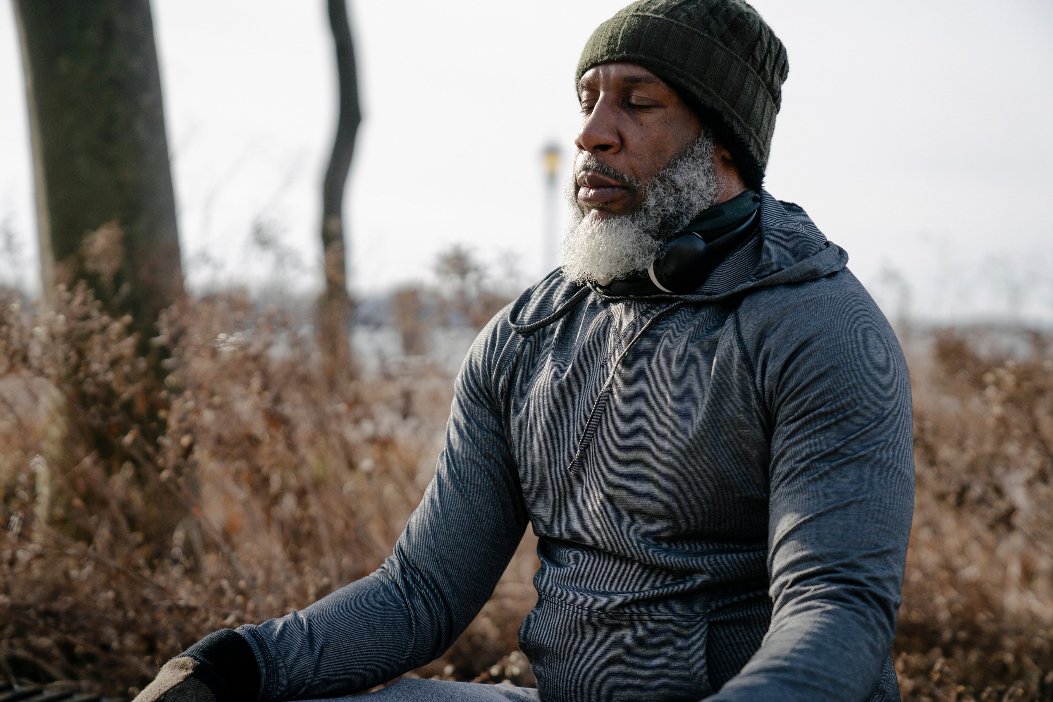 Thoughtful black man in activewear meditating in autumn park